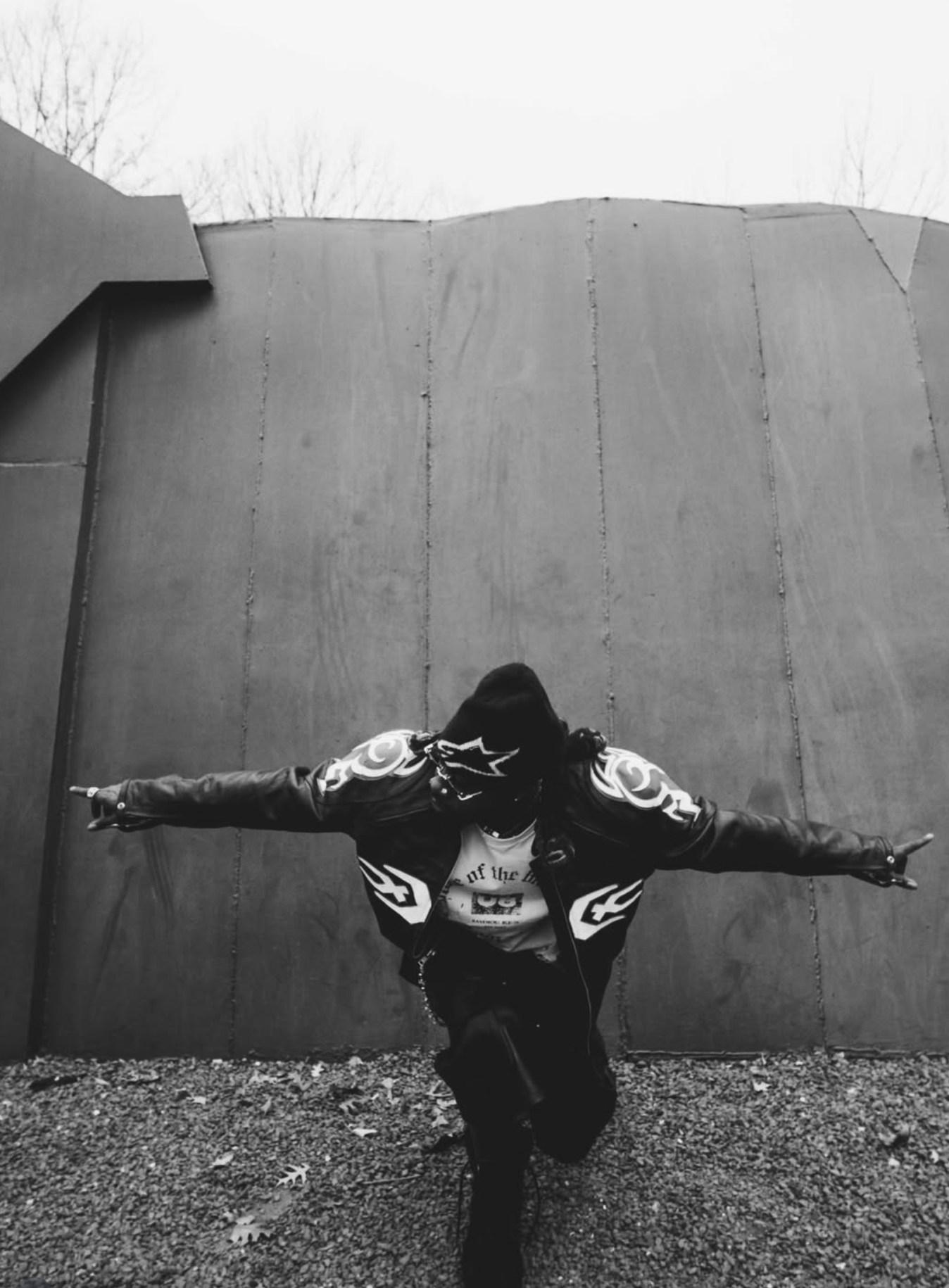 RudeboyFinesse arms outstretched against a concrete wall